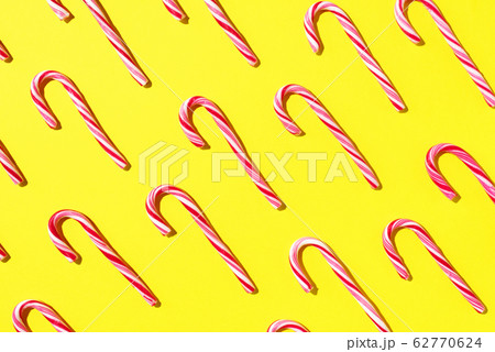 Pattern of Christmas candy cane on yellow background. Top view. Flat lay. Creative minimal concept. Greeting card on Christmas and New Year. Art composition. 62770624