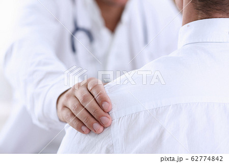 Friendly male doctor hold patient shoulder in office during reception 62774842