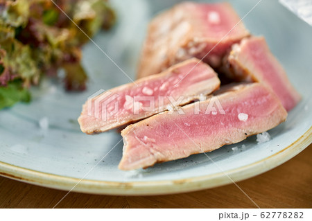 Closeup Medium rare tuna with lettuce and hot sauce. Restaurant menu 62778282
