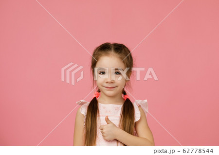 little child girl in dress showing thumbs up 62778544