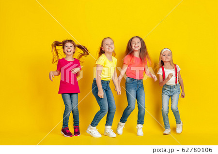 Happy children playing and having fun together on yellow studio background 62780106