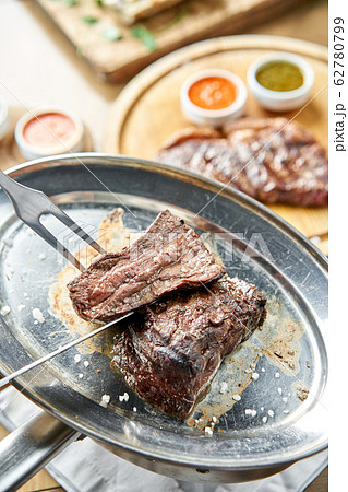 The waiter is butchering griled meat with a knife. Grilled fillet steaks with Pickled cabbage and two sauces.. Barbecue restaurant menu. The waiter is butchering griled meat with a knife. Grilled fillet steaks with Pickled cabbage and two sauces.. Barbecue restaurant menu. 62780799
