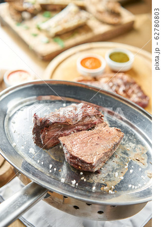 Grilled fillet steaks. A piece of meat cut in two. Barbecue restaurant menu. On a metal plate with coal. Chateaubriand Steak Grilled fillet steaks. A piece of meat cut in two. Barbecue restaurant menu. On a metal plate with coal. Chateaubriand Steak 62780803