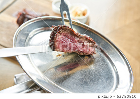 The waiter is butchering griled meat with a knife. Grilled fillet steaks with Pickled cabbage and two sauces.. Barbecue restaurant menu. 62780810