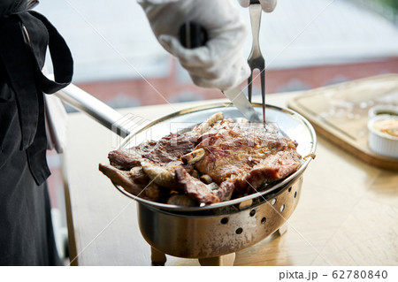 The waiter is butchering with a knife. Various grilled meat set. Barbecue restaurant menu, a series of photos of different meats. 62780840