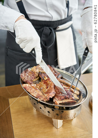 The waiter is butchering with a knife. Set of Various grilled meats . Barbecue restaurant menu, a series of photos of different meats. The waiter is butchering with a knife. Set of Various grilled meats . Barbecue restaurant menu, a series of photos of different meats. 62780841