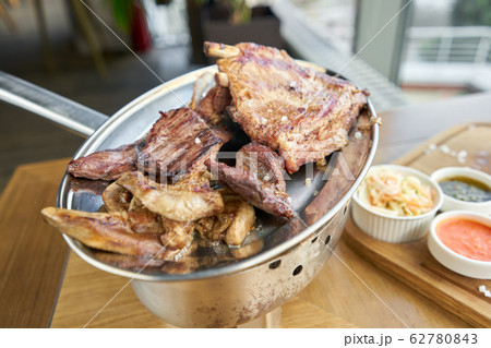 Various grilled meat set heated on coals. Barbecue restaurant menu. Many different food on the table. Dinner party or Banquet Various grilled meat set heated on coals. Barbecue restaurant menu. Many different food on the table. Dinner party or Banquet 62780843