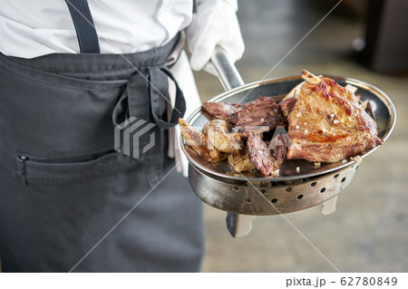The waiter is holding a plate Various grilled meat set. Barbecue restaurant menu, a series of photos of different meats. 62780849