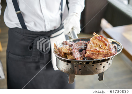 The waiter is holding a plate Various grilled meat set. Barbecue restaurant menu, a series of photos of different meats. The waiter is holding a plate Various grilled meat set. Barbecue restaurant menu, a series of photos of different meats. 62780859