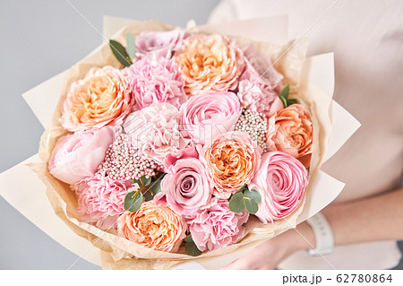 European floral shop. Beautiful bouquet of mixed flowers in womans hands. the work of the florist at a flower shop. Delivery fresh cut flower. 62780864