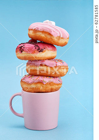 Sweet pink donuts with a pink mug on a blue background. Concept dessert, sweet life, we are what we eat. Blue background, copy space. Sweet pink donuts with a pink mug on a blue background. Concept dessert, sweet life, we are what we eat. Blue background, copy space. 62781585