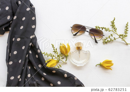 bottle perfume ,sunglasses, black scarf scarf and yellow flower ylang ylang of lifestyle woman 62783251