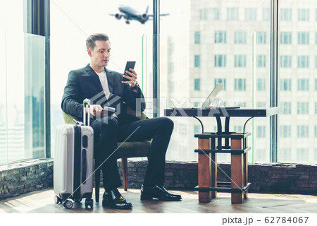 Businessman holding passport and  using smartphone 62784067