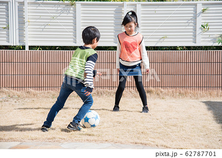 庭でサッカーの練習をする男の子と女の子の写真素材