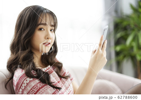 A young lady with a smartphone on the sofa A young lady with a smartphone on the sofa 62788600