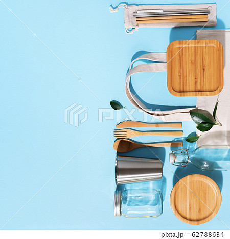 Sustainable lifestyle. Zero waste, plastic free shopping concept. Cotton bags, glass jar, bottle, metal cup, straws for drinking, bamboo cutlery and boxes on blue background Sustainable lifestyle. Zero waste, plastic free shopping concept. Cotton bags, glass jar, bottle, metal cup, straws for drinking, bamboo cutlery and boxes on blue background 62788634
