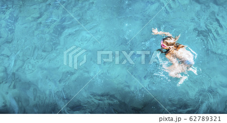 Young girl in swimwear lying in blue water, aerial view 62789321