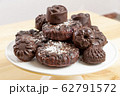Delicious chocolate dietary candies and cookies for vegans made from natural ingredients. Tasty treats, sprinkled with coconut, on a white tray on wooden table. Healthy meal. Sweet and harmless. 62791572