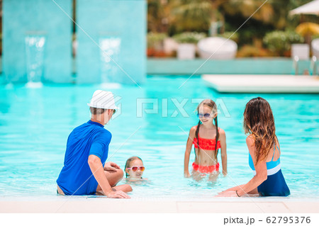 Happy family of four in outdoors swimming pool Happy family of four in outdoors swimming pool 62795376