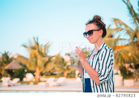 Young beautiful woman enjoying summer vacation in luxury swimming pool 62795823