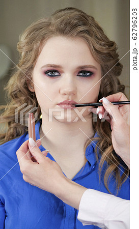 Applying makeup. The model's lips are painted with 62796203