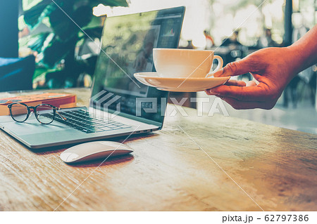 Waiter hand serving coffee with laptop and glasses on working table in cafe. 62797386