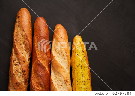 Three crispy french baguettes lie on an old wooden Three crispy french baguettes lie on an old wooden 62797584