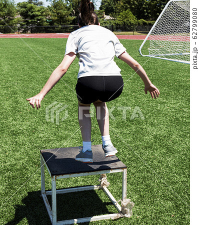 Young female athlete jumping on to a plyo box 62799080