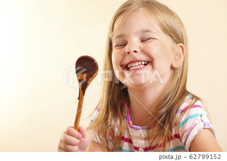 Cheerful girl eating chocolate sauce Cheerful girl eating chocolate sauce 62799152