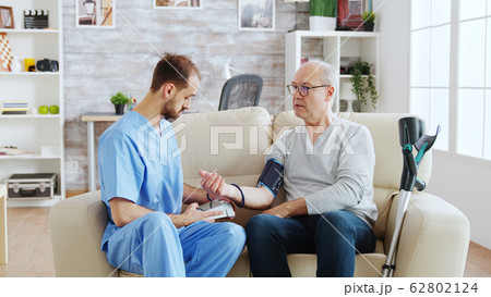 Male nurse measuring blood pressure of a man pensioner 62802124