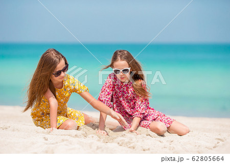 Two little happy girls have a lot of fun at tropical beach playing together Two little happy girls have a lot of fun at tropical beach playing together 62805664