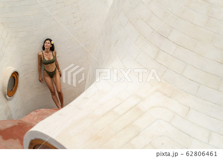 Calm young woman standing near a limestone wall 62806461
