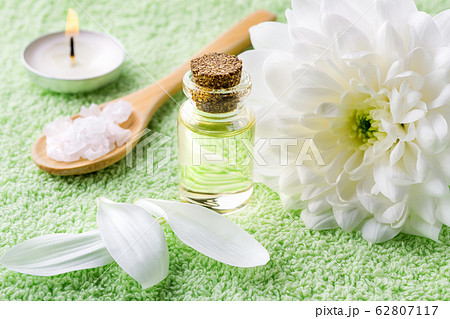 Close-up of chrysanthemum essential oil, white chrysanthemum, sea salt and burning aromatic candle Close-up of chrysanthemum essential oil, white chrysanthemum, sea salt and burning aromatic candle 62807117
