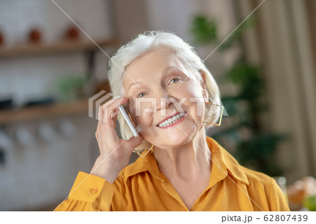 Cheerful elderly woman talking on the phone with her friend 62807439