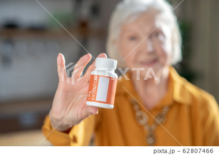 Grey-haired good-looking woman holding a jar with vitamins in her hands 62807466