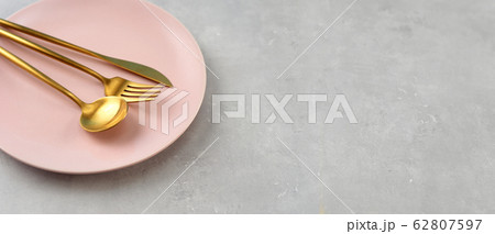 Beautiful pink plate and gold cutlery on grey Beautiful pink plate and gold cutlery on grey 62807597