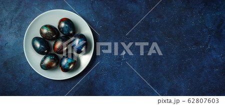 Creative Easter eggs in a plate on dark blue 62807603
