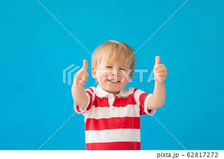 Happy child wearing striped shirt against blue Happy child wearing striped shirt against blue 62817272
