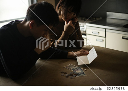 通帳を見て悩む夫婦 通帳を見て悩む夫婦 62825938