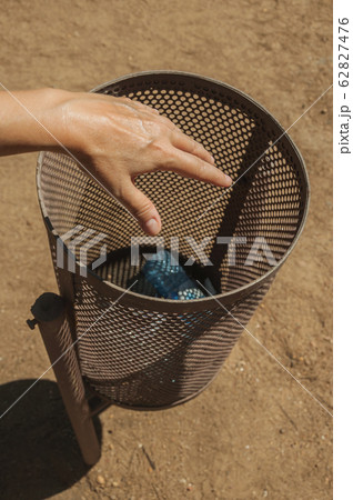Hand of woman throwing a plastic bottle in a trash can at Merida Hand of woman throwing a plastic bottle in a trash can at Merida 62827476