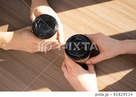 コーヒーの紙カップを持った２人の手 62829514