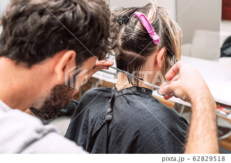 Master hairdresser cuts hair of blond woman in salon. Close up photo Master hairdresser cuts hair of blond woman in salon. Close up photo 62829518