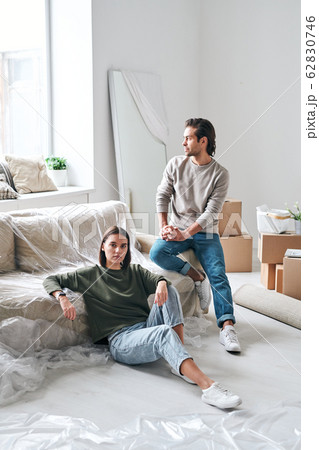 Young tired woman and her husband in casualwear having rest by couch by window 62830746