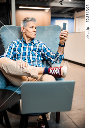 Adult man holding smartphone while resting in cafe 62831396