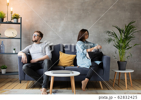 A young Couple are Sitting on the Couch After an Argument at Home. The husband and Wife Sit with their Backs to Each other. A young Couple are Sitting on the Couch After an Argument at Home. The husband and Wife Sit with their Backs to Each other. 62832425