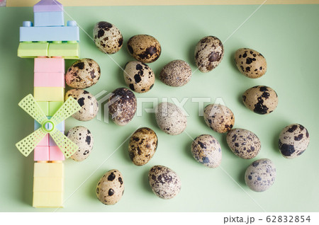 heap of quail eggs and toy on color background. heap of quail eggs and toy on color background. 62832854