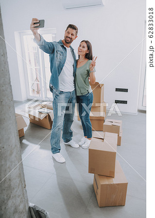 Happy couple is using mobile phone in new flat Happy couple is using mobile phone in new flat 62833018