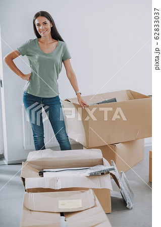 Happy young lady is standing with many boxes indoors 62833037