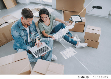 Young man holding laptop while sitting on floor Young man holding laptop while sitting on floor 62833065