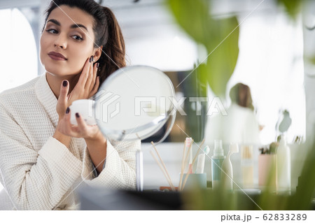 Smiling beautiful woman is holding cream jar Smiling beautiful woman is holding cream jar 62833289